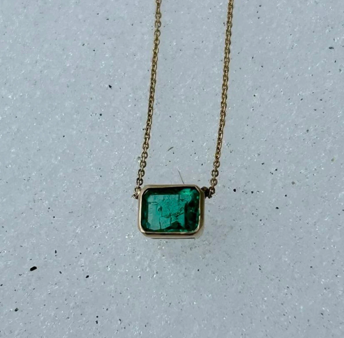 14K gold emerald necklace on concrete